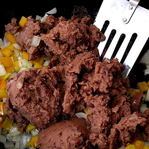 Adding the canned beans to the vegetables